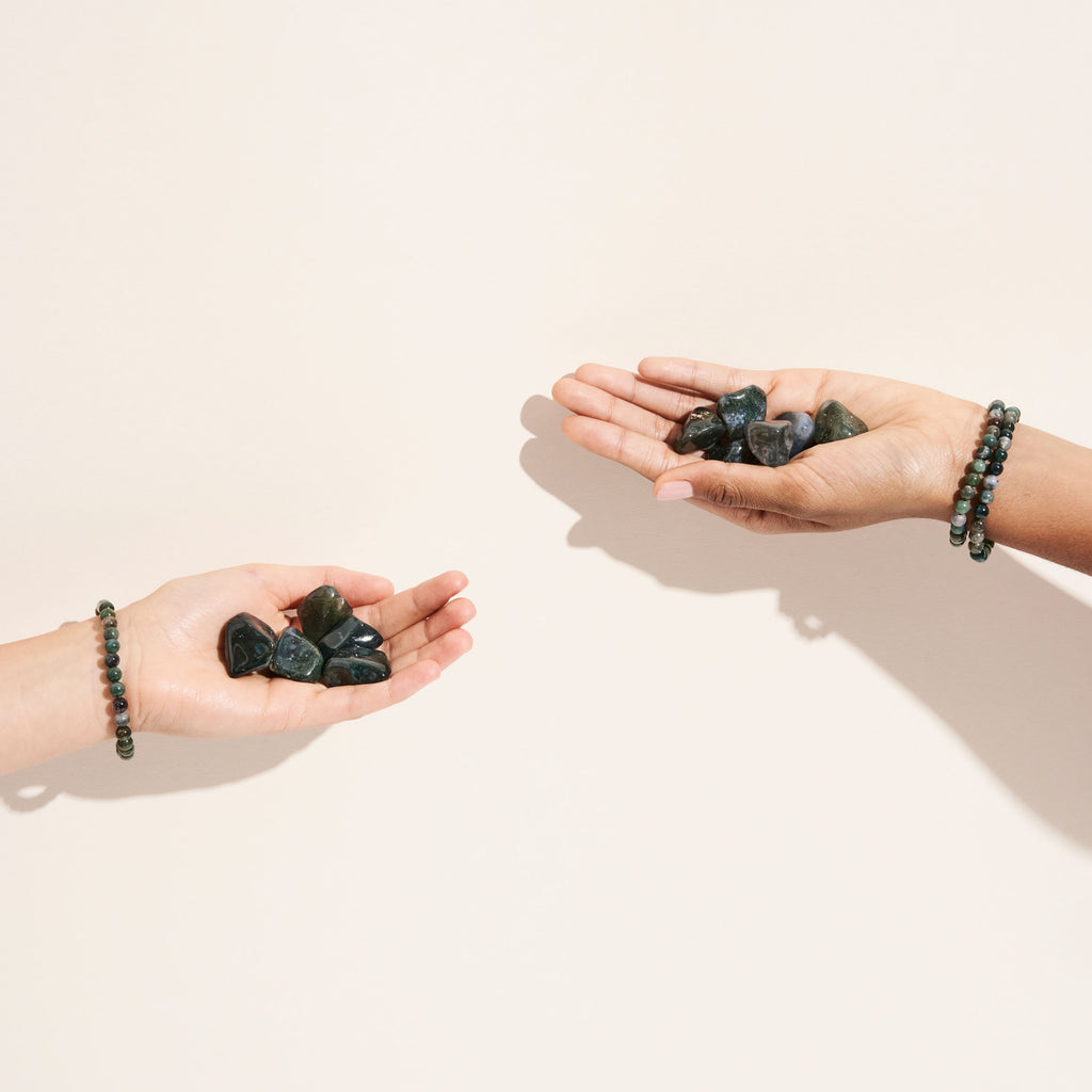 Photo de pierres d'Agate Mousse roulées tenues dans des mains et de bracelets d'Agate Mousse portés aux poignets