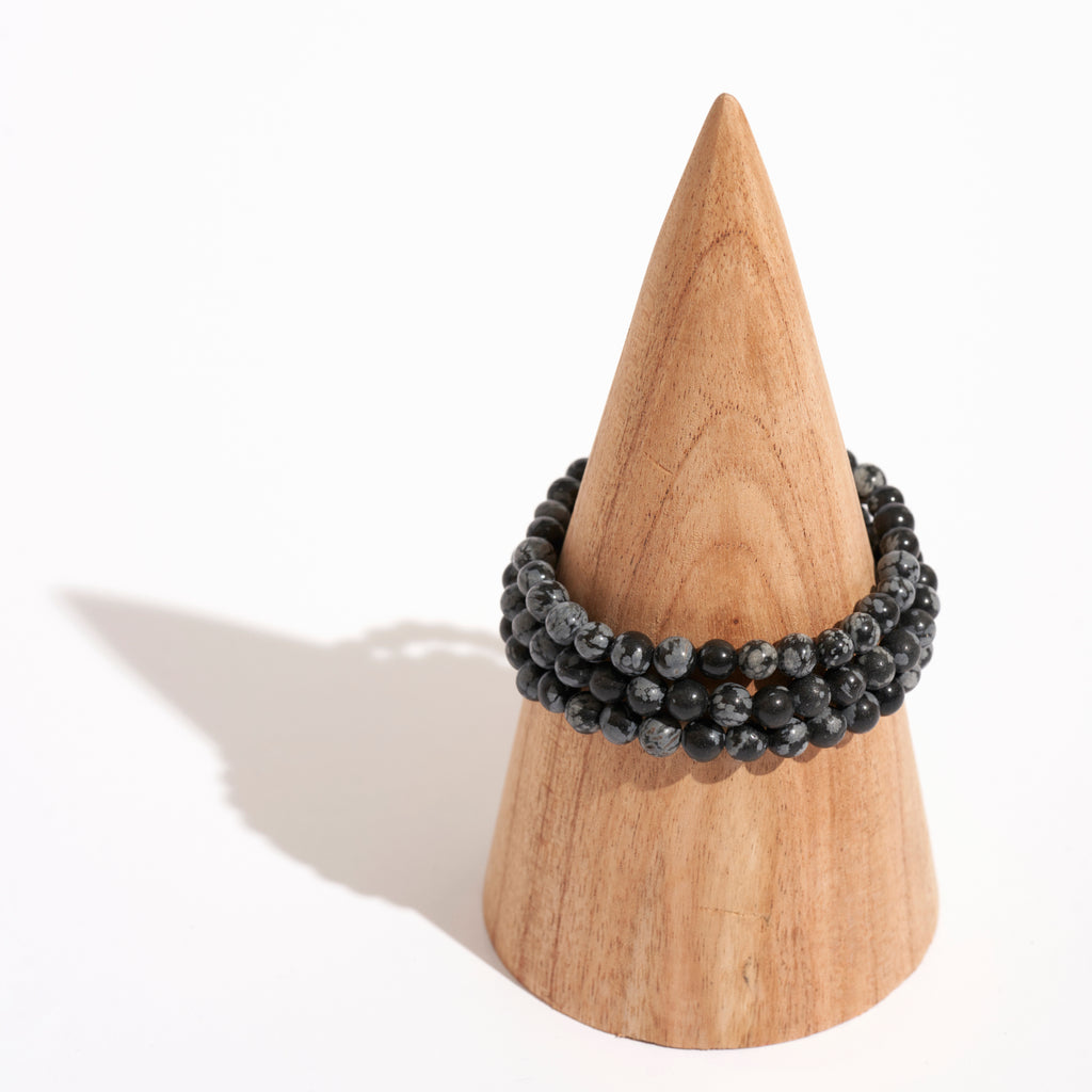Photo de plusieurs bracelets de pierre d'Obsidienne Flocon de Neige sur un portant en bois