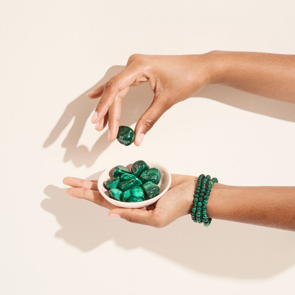 Photo de bracelets et pierres de Malachite tenues par des mains dans une coupelle