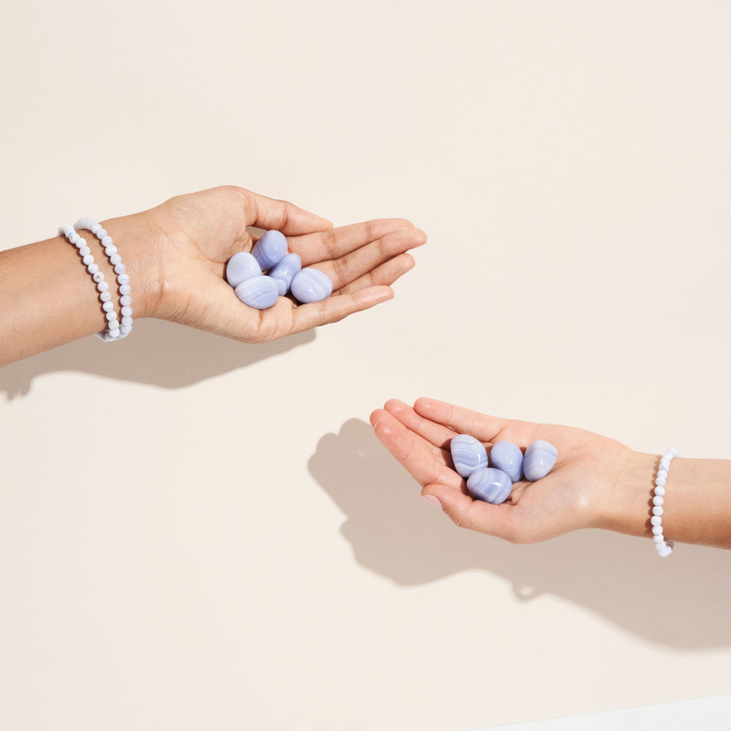 Photo de différentes pierres de Calcédoines bleues tenues par des mains portant cette même pierre en bracelet- Let's play on the moon