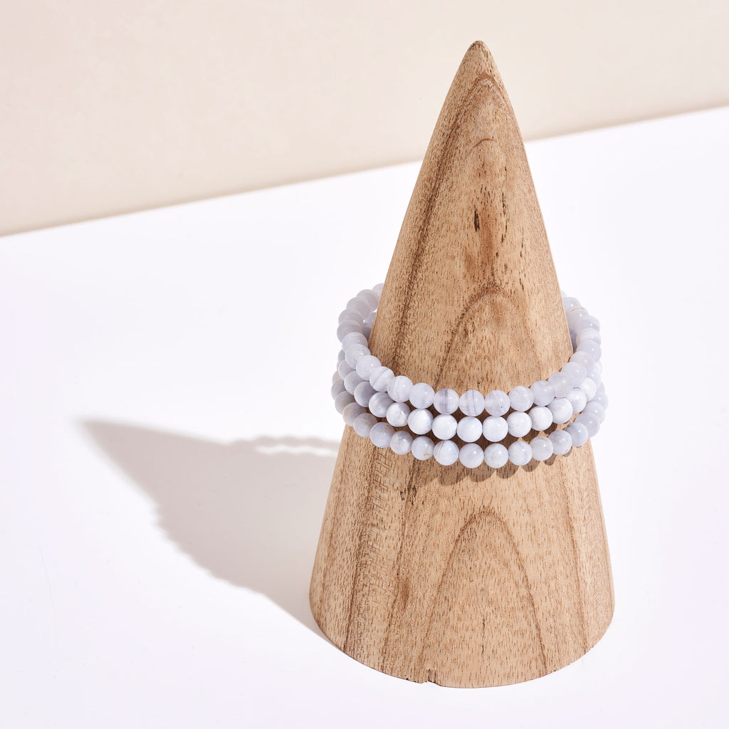 Photo de bracelets de pierre de Calcédoine Bleue autour d'un portant en bois 